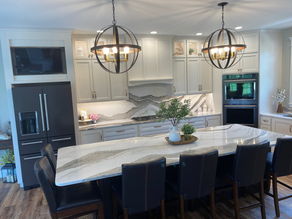 Example of a large transitional l-shaped medium tone wood floor and brown floor open concept kitchen design with an undermount sink, flat-panel cabinets, white cabinets, quartz countertops, multicolored backsplash, quartz backsplash, black appliances, an island and multicolored countertops