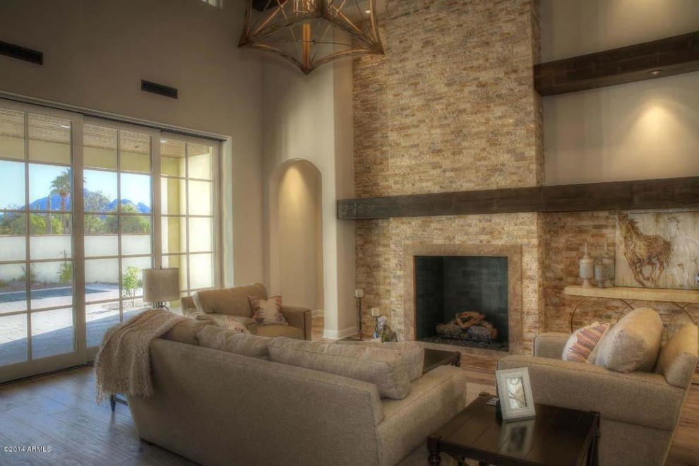 Example of a large transitional formal and open concept light wood floor living room design in Phoenix with a stone fireplace