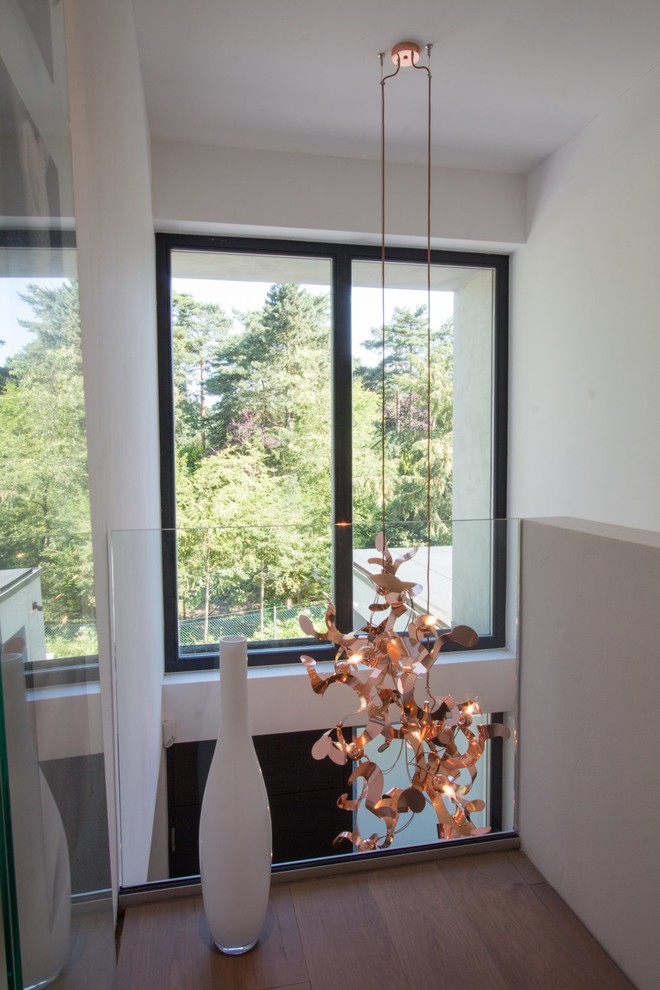 Großes Modernes Foyer mit weißer Wandfarbe, hellem Holzboden, Einzeltür, schwarzer Haustür und braunem Boden in Hamburg