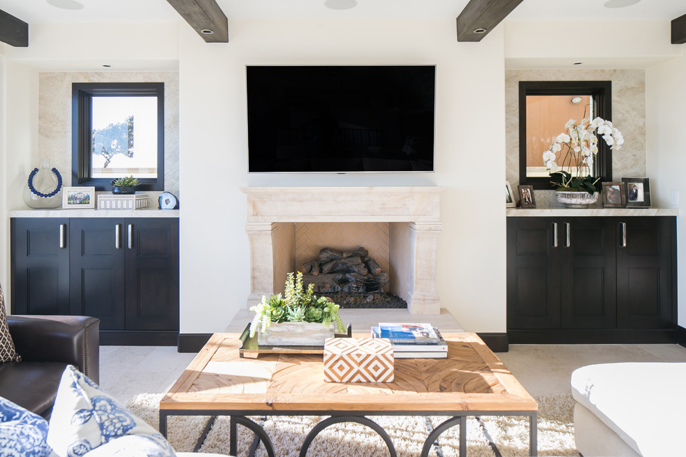 Photo of a mid-sized beach style open concept living room in Orange County with beige walls, travertine floors, a standard fireplace, a stone fireplace surround and a wall-mounted tv.
