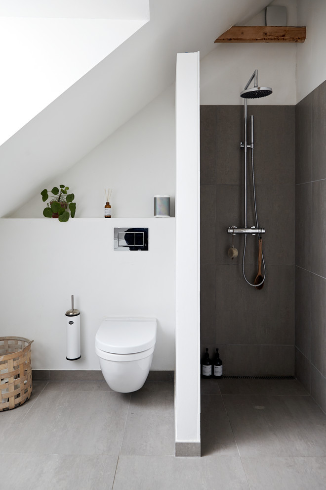 Inspiration for a mid-sized scandinavian 3/4 bathroom in Aarhus with an alcove shower, a wall-mount toilet, gray tile, concrete floors, grey floor, an open shower and white walls.