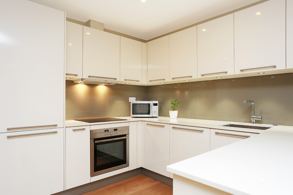Mid-sized modern u-shaped eat-in kitchen in London with glass-front cabinets and a peninsula.