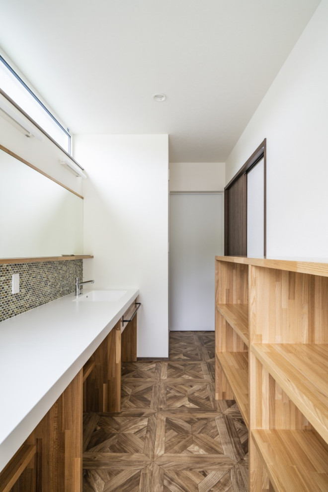 Inspiration for a mid-sized modern single-wall dedicated laundry room in Other with open cabinets, light wood cabinets, solid surface benchtops, white walls, vinyl floors, brown floor, white benchtop, wallpaper and wallpaper.