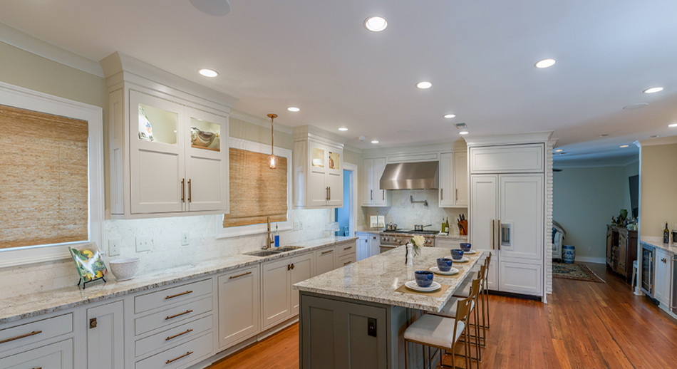 Inspiration for a transitional medium tone wood floor and brown floor eat-in kitchen remodel with an undermount sink, recessed-panel cabinets, white cabinets, granite countertops, white backsplash, stainless steel appliances, an island and beige countertops