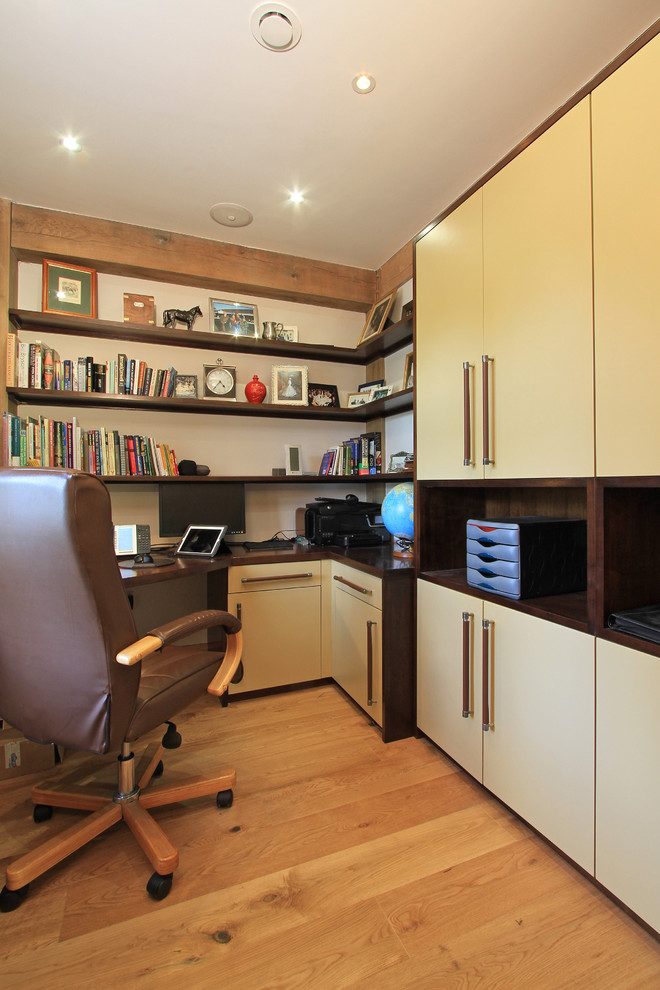 Mid-sized contemporary study room in Hampshire with white walls, medium hardwood floors and a built-in desk.