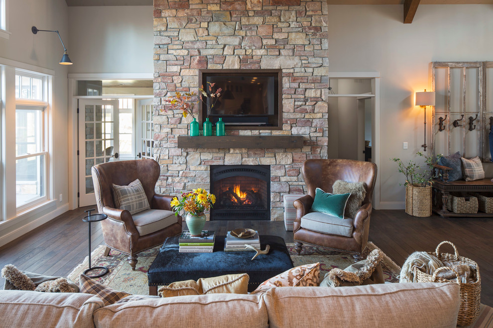 This is an example of a country formal open concept living room in Minneapolis with medium hardwood floors, a standard fireplace, a stone fireplace surround and a wall-mounted tv.