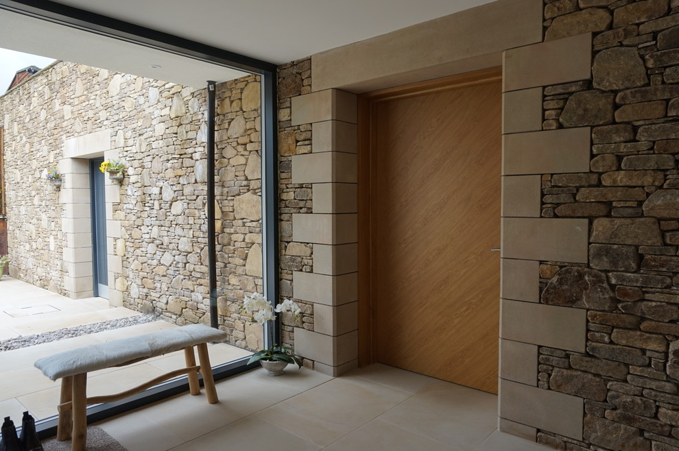 This is an example of a large contemporary foyer in Other with beige walls, limestone floors, a single front door, a gray front door and beige floor.