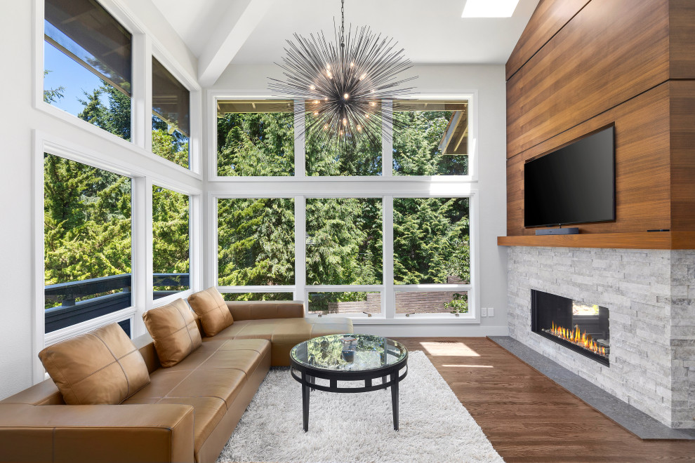 Modelo de sala de estar abierta retro con suelo de madera en tonos medios, chimenea de doble cara y marco de chimenea de piedra