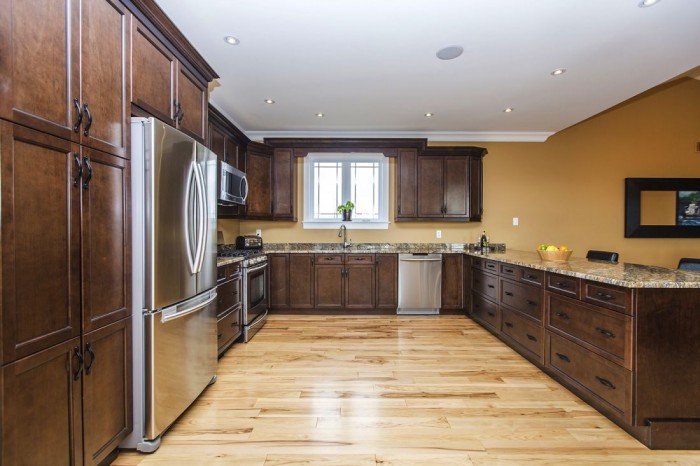 Inspiration for a traditional eat-in kitchen in Ottawa with an undermount sink, recessed-panel cabinets, dark wood cabinets, granite benchtops, stainless steel appliances, light hardwood floors and a peninsula.