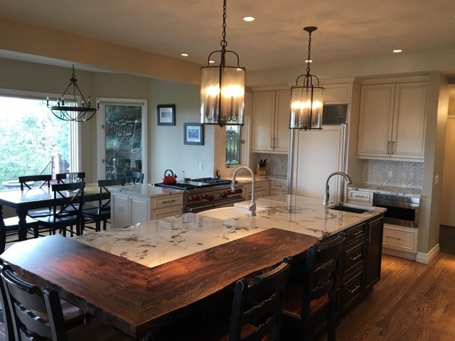 Kitchen - mid-sized transitional u-shaped medium tone wood floor kitchen idea in Denver with a farmhouse sink, raised-panel cabinets, white cabinets, marble countertops, white backsplash, stone tile backsplash, paneled appliances and an island