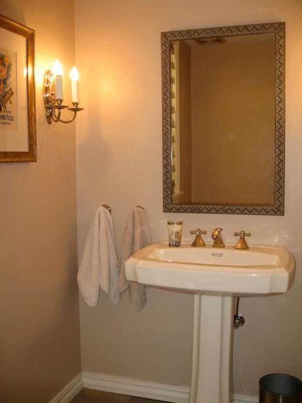Photo of a mid-sized traditional powder room in Milwaukee with a two-piece toilet, a pedestal sink, beige walls, porcelain floors and brown floor.