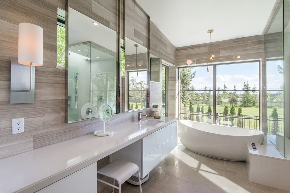 This is an example of a mid-sized contemporary master bathroom in Salt Lake City with flat-panel cabinets, white cabinets, a freestanding tub, porcelain floors, an undermount sink, engineered quartz benchtops, a corner shower, a wall-mount toilet, gray tile and grey walls.