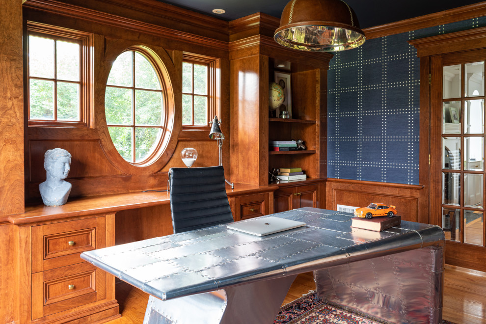 Mittelgroßes Klassisches Arbeitszimmer mit Arbeitsplatz, blauer Wandfarbe, braunem Holzboden, freistehendem Schreibtisch, braunem Boden und Tapetenwänden in Philadelphia