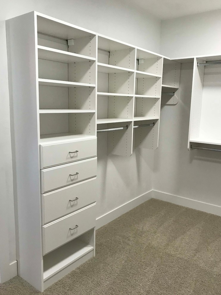 This is an example of a mid-sized arts and crafts gender-neutral walk-in wardrobe in Other with carpet and grey floor.