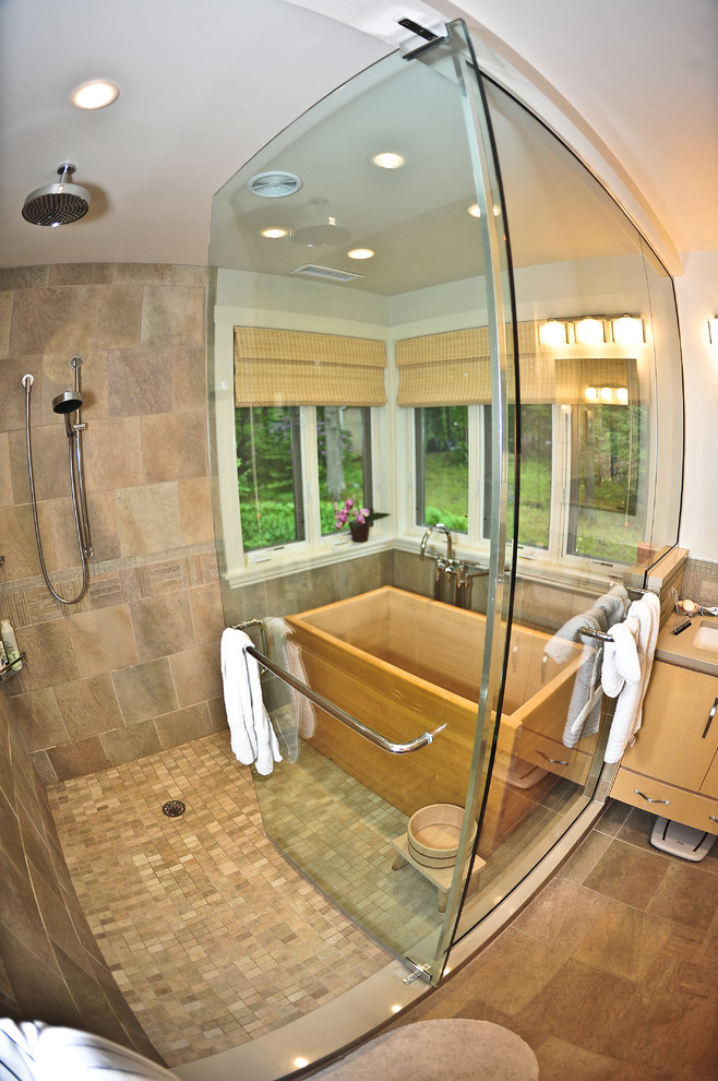 Пример оригинального дизайна: огромная ванная комната в современном стиле с японской ванной, двойным душем, врезной раковиной, светлыми деревянными фасадами, столешницей из дерева, унитазом-моноблоком, разноцветной плиткой и каменной плиткой