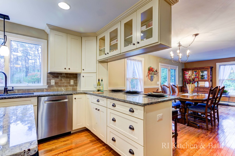 Example of a large transitional u-shaped light wood floor eat-in kitchen design in Providence with an undermount sink, shaker cabinets, beige cabinets, granite countertops, brown backsplash, porcelain backsplash, stainless steel appliances and an island