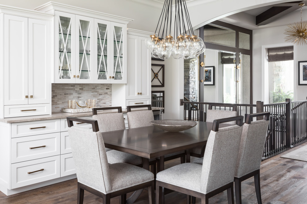 This is an example of a transitional dining room in Kansas City with white walls, dark hardwood floors and brown floor.