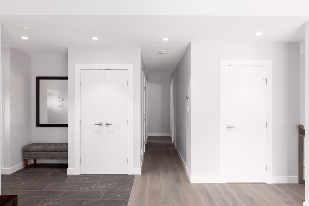 This is an example of a mid-sized modern front door in Vancouver with white walls, laminate floors, a single front door, a medium wood front door and grey floor.