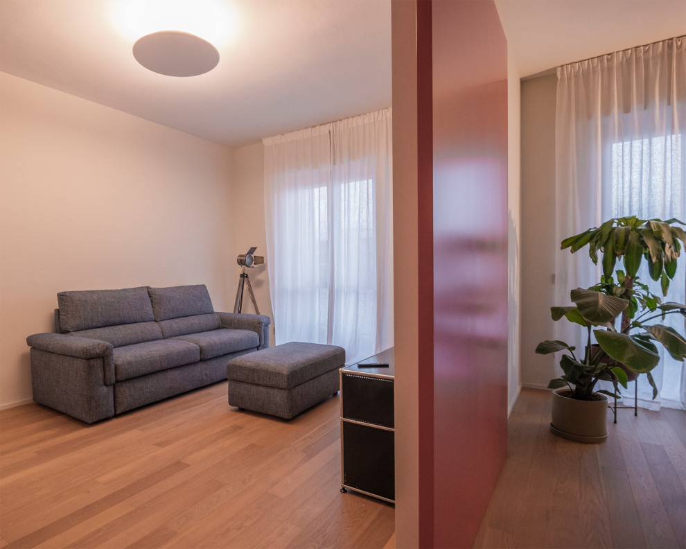 Modern inredning av ett mellanstort allrum med öppen planlösning, med beige väggar, ljust trägolv, en fristående TV och brunt golv