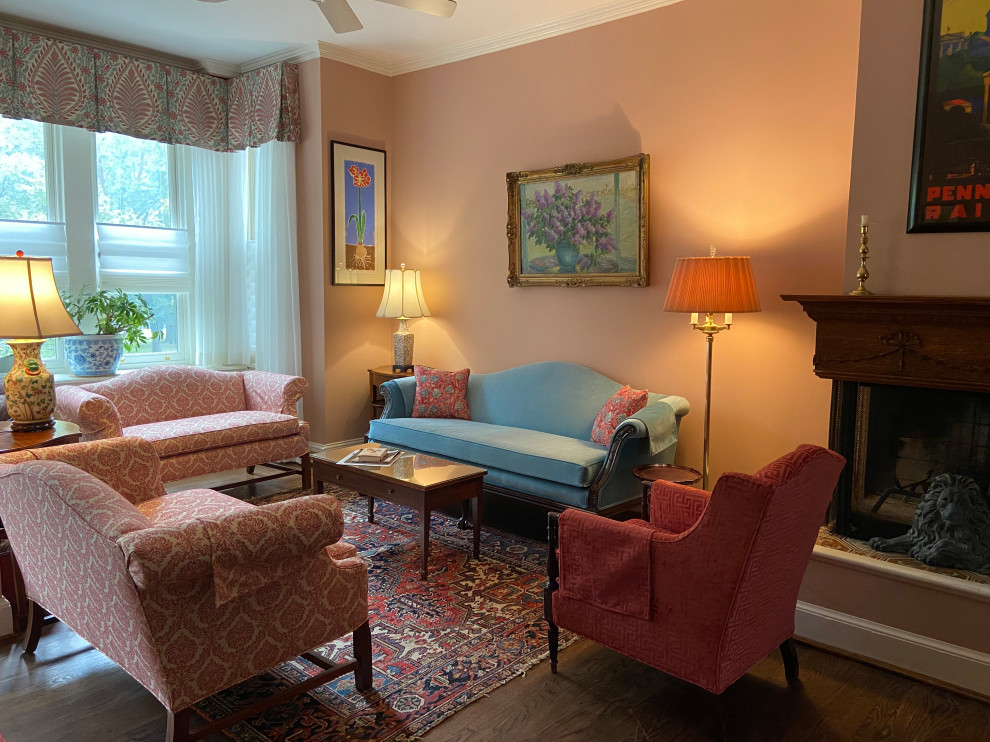 Immagine di un piccolo soggiorno classico aperto con pareti rosa, parquet scuro, camino bifacciale, cornice del camino in legno e TV autoportante