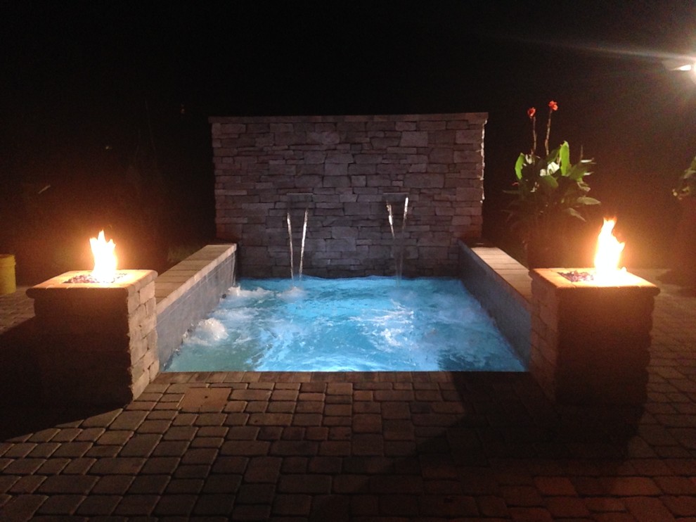 Photo of a small contemporary backyard rectangular pool in Jacksonville with brick pavers and a hot tub.