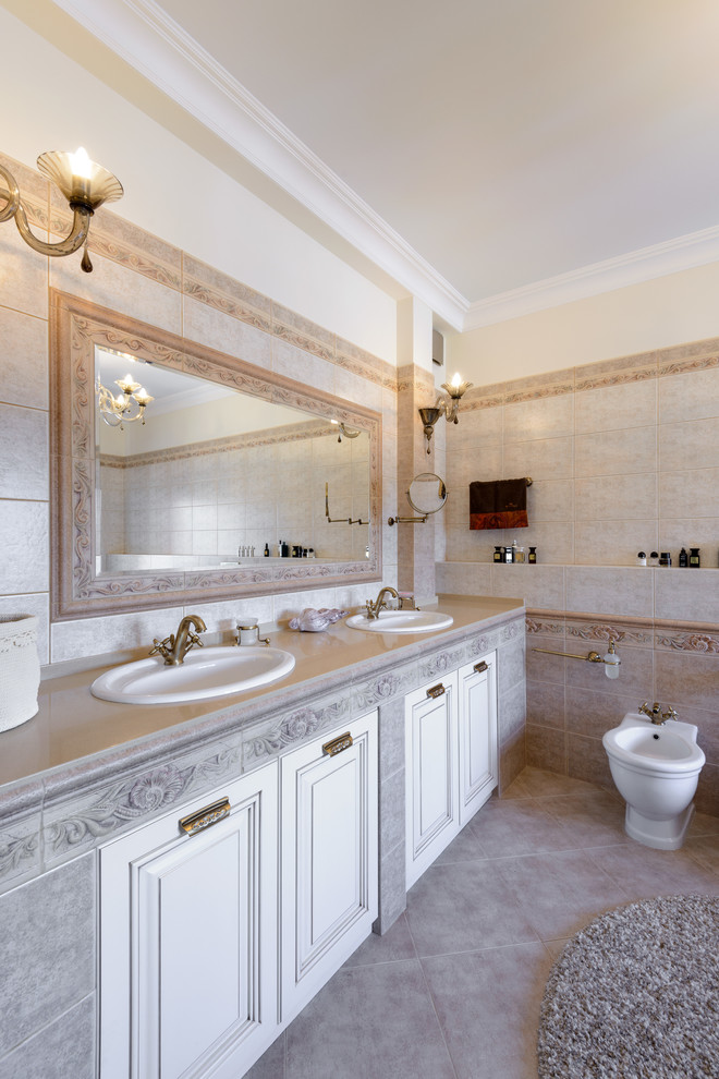 This is an example of a large traditional master bathroom in Novosibirsk with white cabinets, a claw-foot tub, beige tile, ceramic tile, beige walls, ceramic floors, an undermount sink and solid surface benchtops.