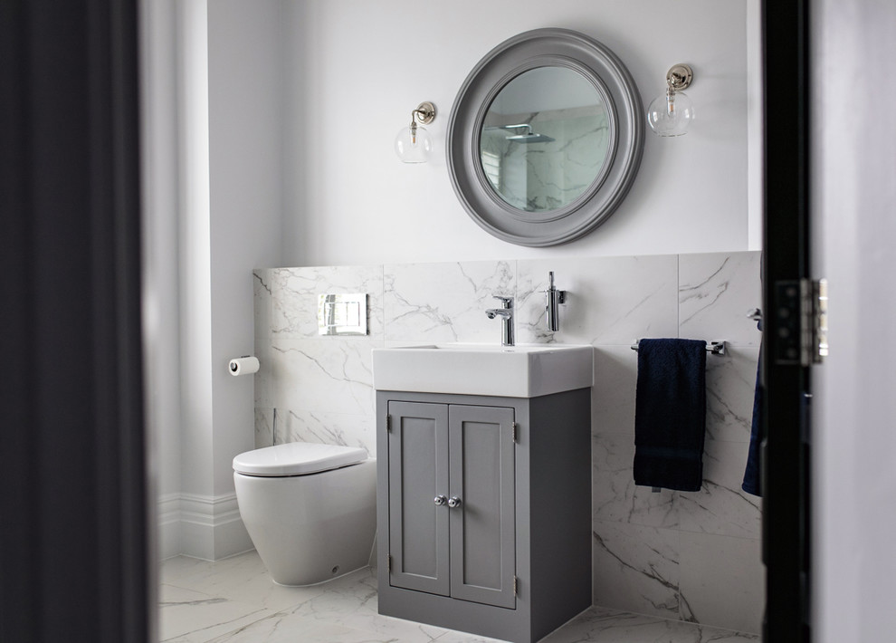 Inspiration for a transitional powder room in Surrey with shaker cabinets, grey cabinets, a one-piece toilet, white tile, white walls, white benchtops, marble, ceramic floors and white floor.