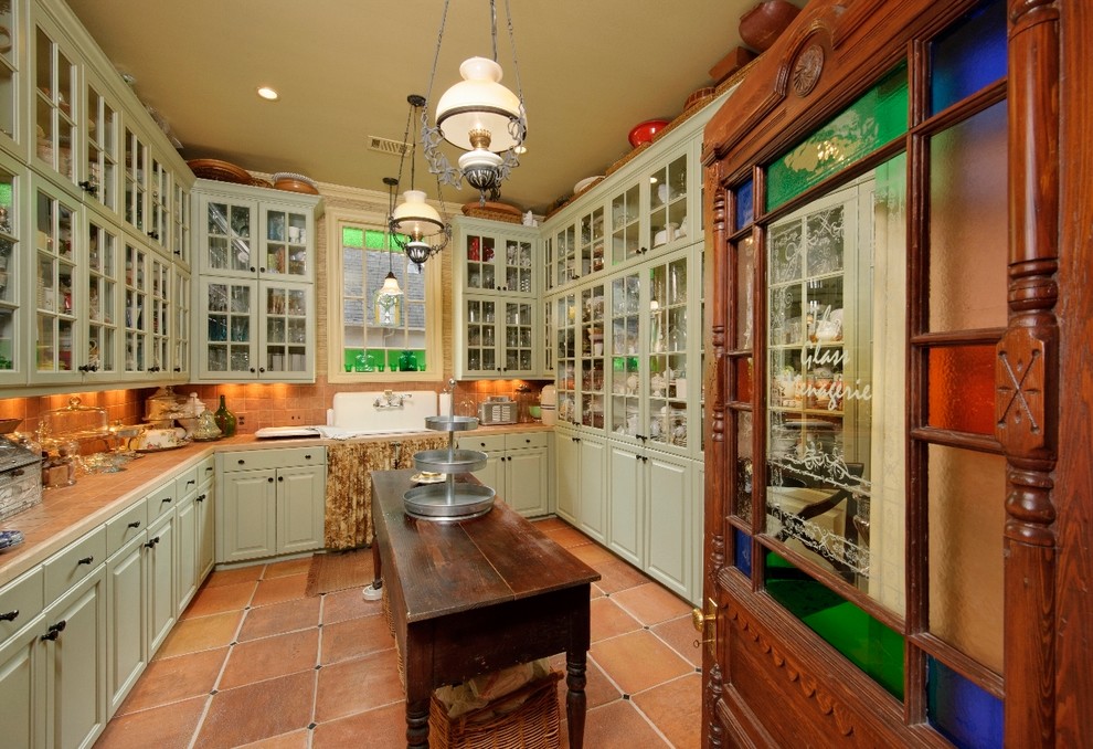 Inspiration for a mediterranean galley separate kitchen in Houston with glass-front cabinets, green cabinets and a farmhouse sink.