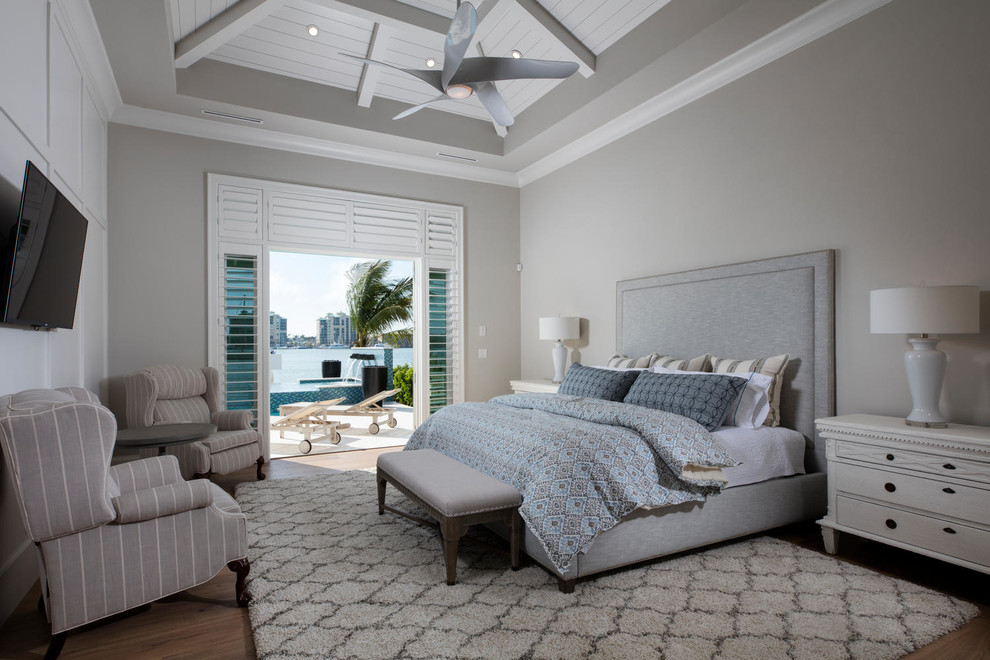 This is an example of a beach style master bedroom in Miami with grey walls, medium hardwood floors and no fireplace.