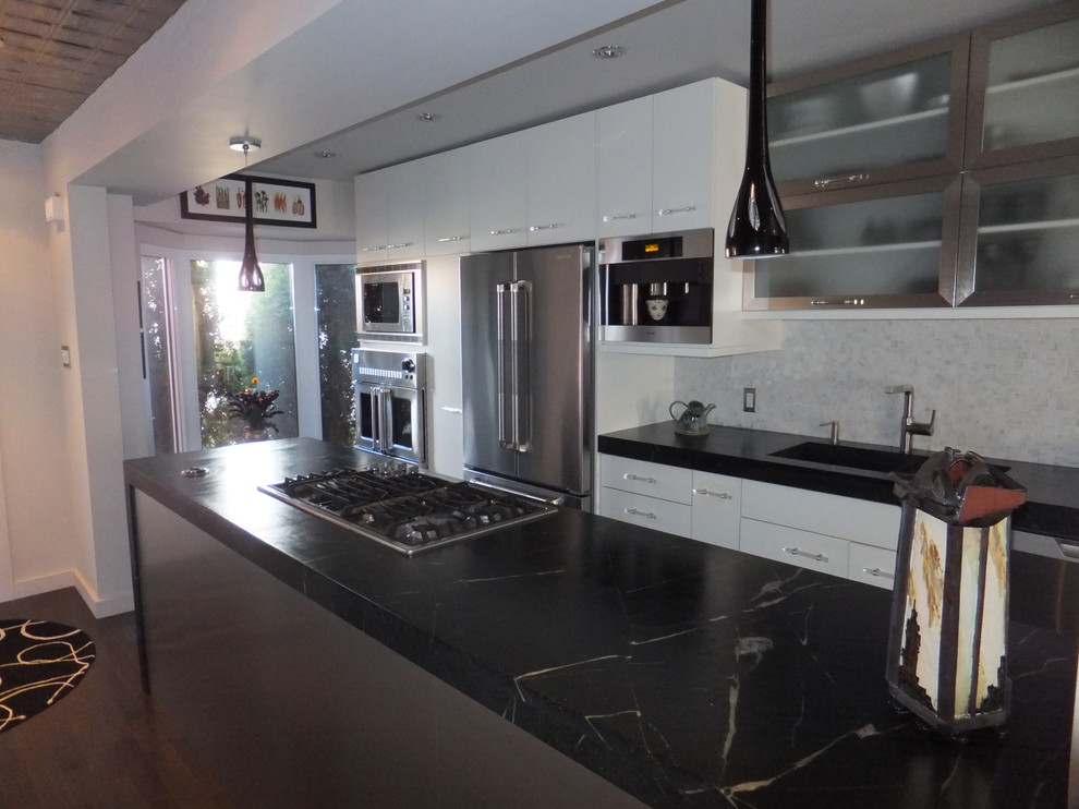 Mid-sized transitional galley dark wood floor and brown floor eat-in kitchen photo in Toronto with an undermount sink, flat-panel cabinets, white cabinets, quartzite countertops, white backsplash, mosaic tile backsplash, stainless steel appliances, a peninsula and black countertops
