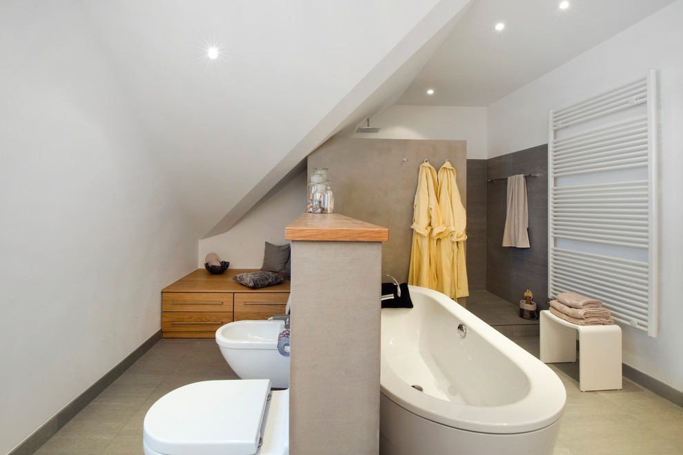 Photo of a contemporary bathroom in Munich with a freestanding tub, an open shower and a wall-mount toilet.