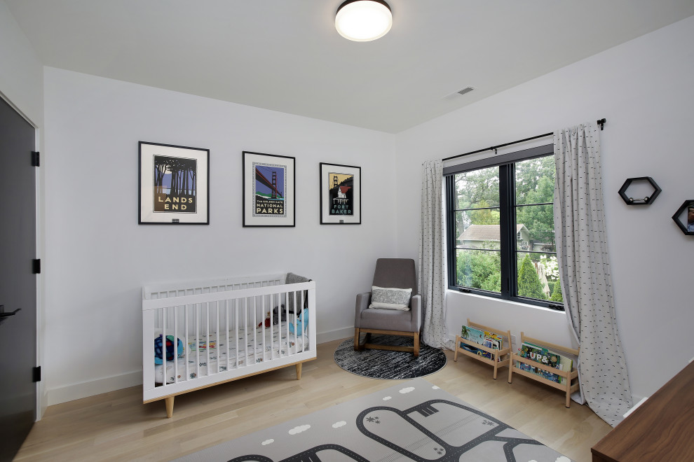 This is an example of a large modern nursery for boys in Chicago with blue walls and light hardwood flooring.