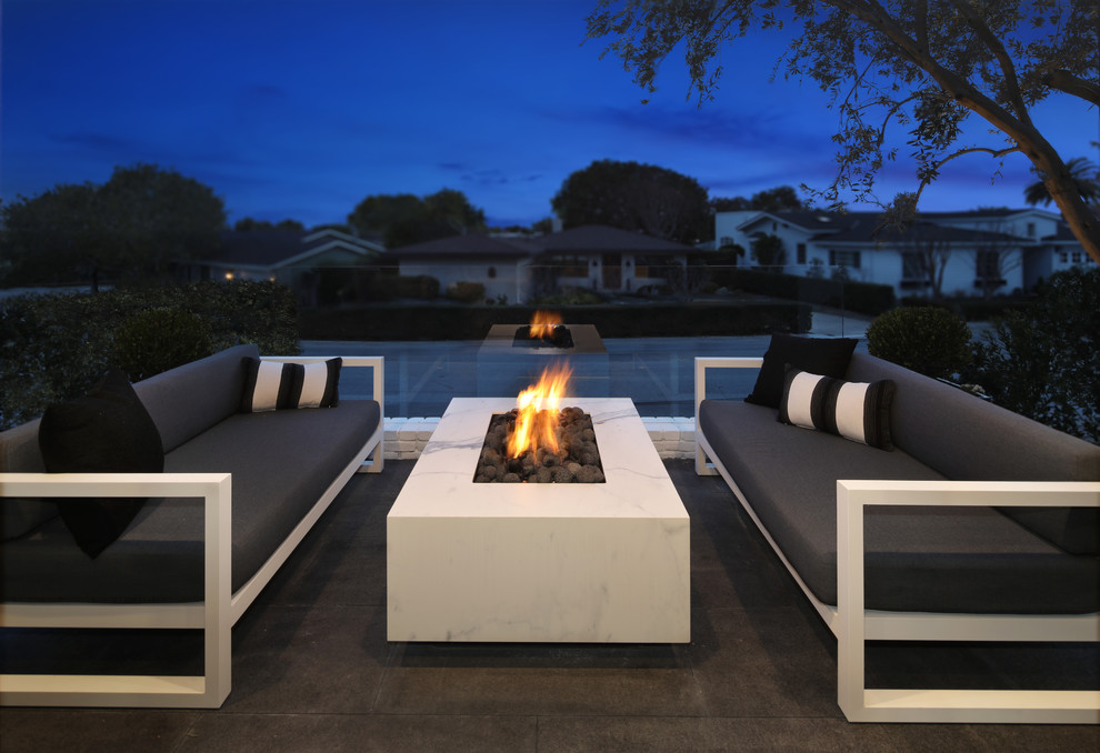 Design ideas for a mid-sized modern front yard patio in Orange County with a fire feature, natural stone pavers and no cover.