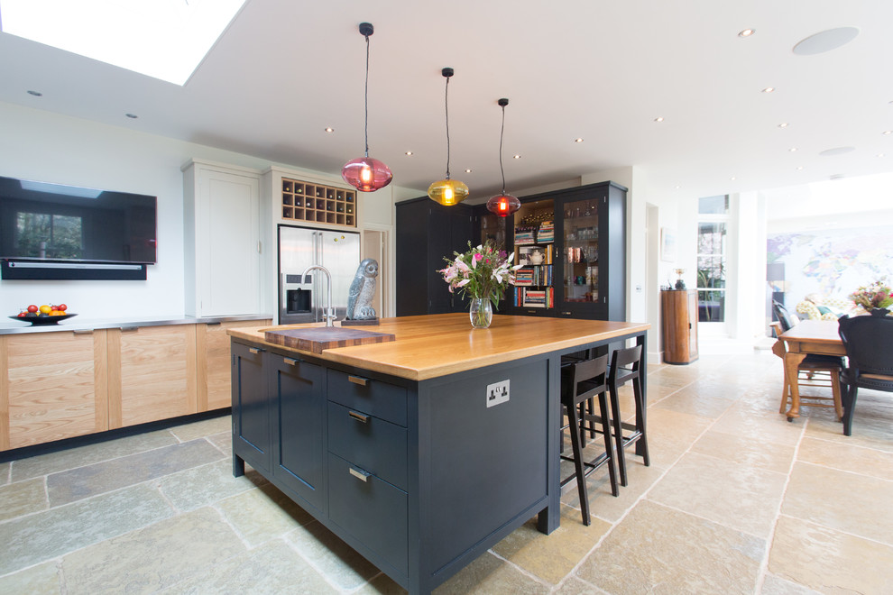 This is an example of a large eclectic u-shaped open plan kitchen in Surrey with an integrated sink, shaker cabinets, black cabinets, stainless steel benchtops, metallic splashback, glass tile splashback, stainless steel appliances, terrazzo floors and with island.