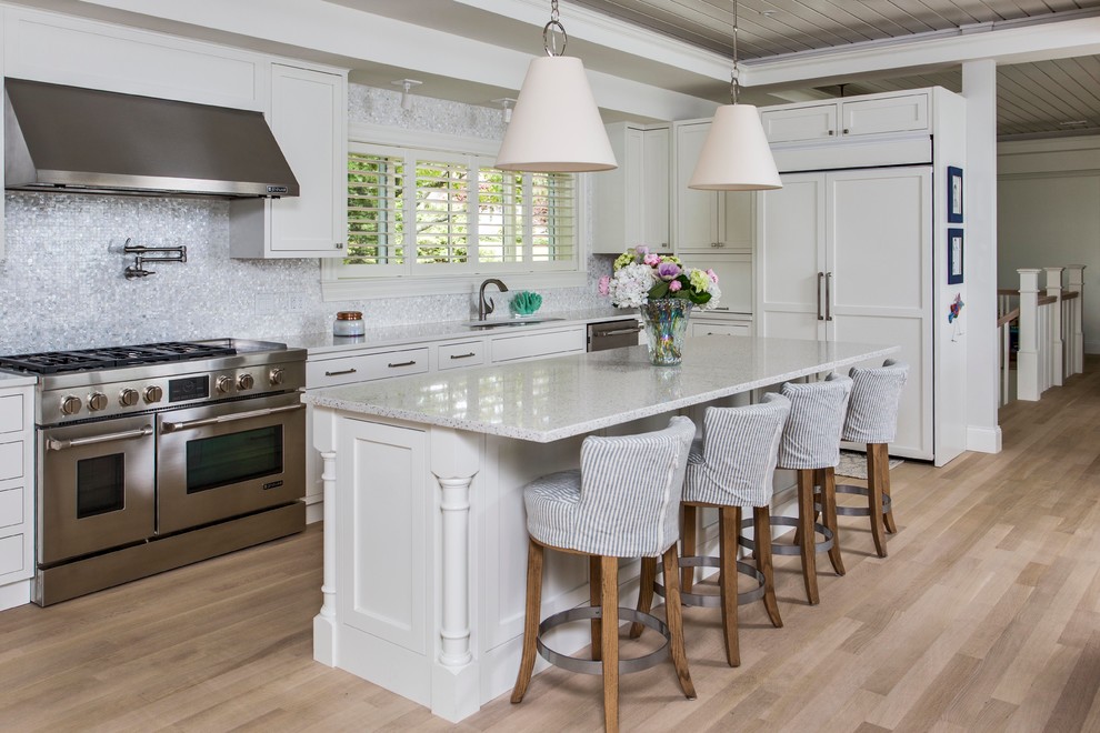 Kitchen - coastal light wood floor kitchen idea in Portland Maine with shaker cabinets, white cabinets, gray backsplash, paneled appliances and an island
