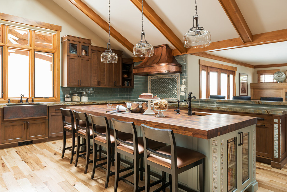 This is an example of an arts and crafts l-shaped open plan kitchen in Salt Lake City with a farmhouse sink, shaker cabinets, dark wood cabinets, wood benchtops, green splashback, subway tile splashback, light hardwood floors, with island and beige floor.