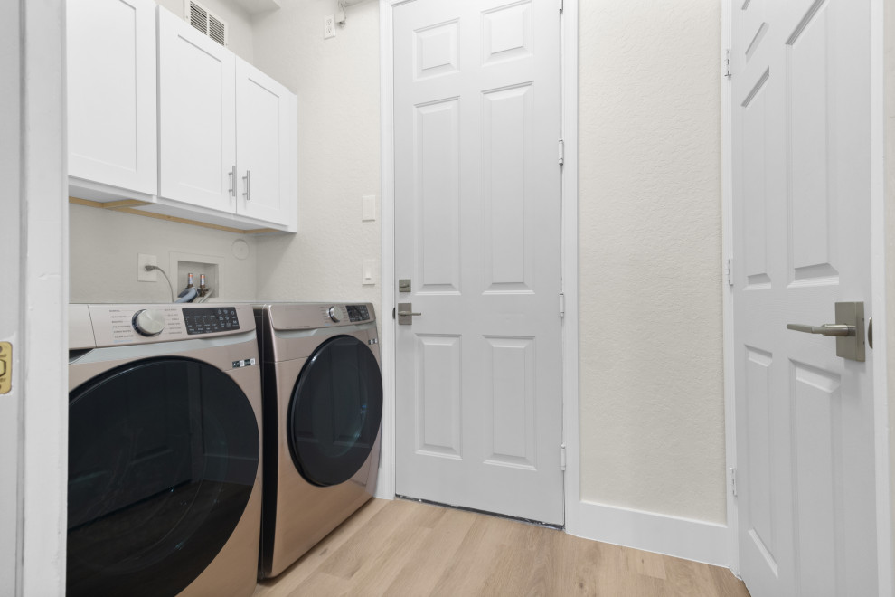 Idéer för mellanstora minimalistiska linjära tvättstugor enbart för tvätt, med luckor med profilerade fronter, vita skåp, vita väggar, vinylgolv, en tvättmaskin och torktumlare bredvid varandra och beiget golv