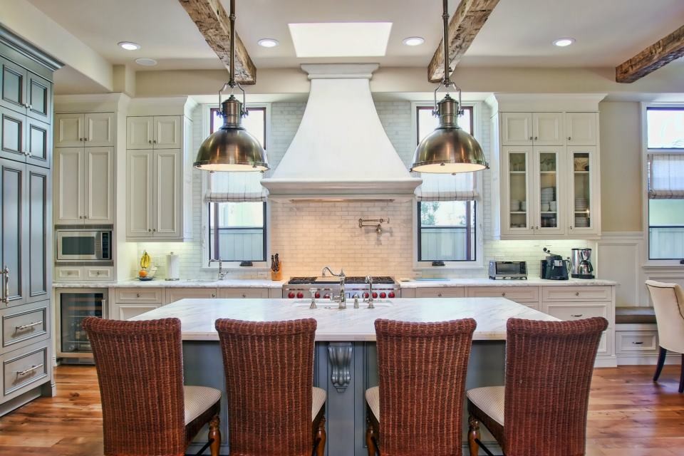 Inspiration for a large transitional kitchen in Los Angeles with a farmhouse sink, marble benchtops, white splashback, stone tile splashback, stainless steel appliances and medium hardwood floors.