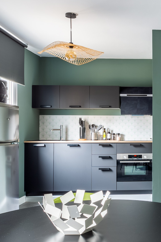 Photo of a small contemporary single-wall eat-in kitchen in Marseille with an undermount sink, wood benchtops, vinyl floors, grey floor, flat-panel cabinets, black cabinets, white splashback, stainless steel appliances, no island and beige benchtop.
