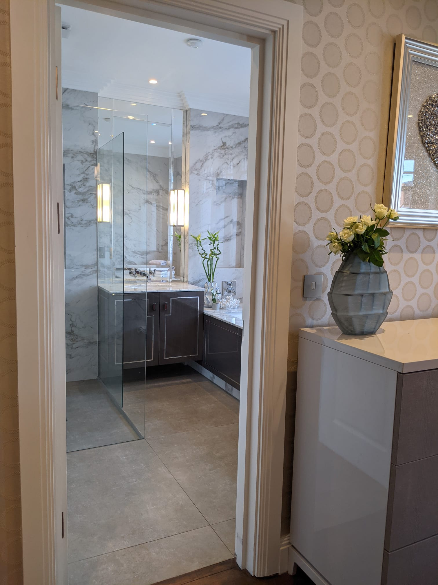 Carrara marble bathroom with walnut floating vanity and walnut bath panel with chrome inlays