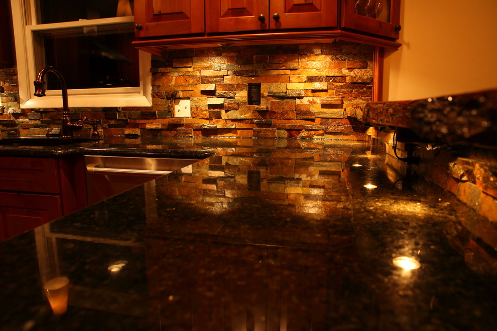 Small mountain style u-shaped eat-in kitchen photo with a single-bowl sink, raised-panel cabinets, medium tone wood cabinets, granite countertops, multicolored backsplash, stone slab backsplash, stainless steel appliances and no island