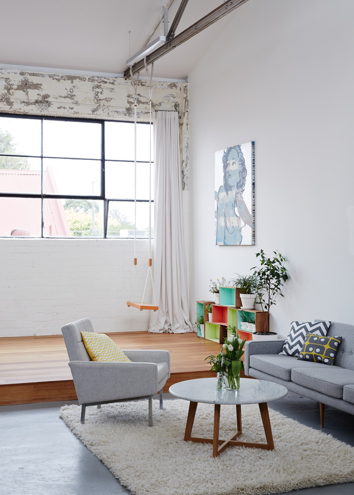 Industrial formal living room in Melbourne with white walls and concrete floors.