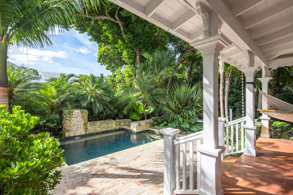 Mid-sized tropical side yard rectangular pool in Miami with brick pavers.