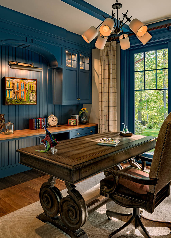 Design ideas for a beach style home office in Boston with a library, blue walls, medium hardwood floors, no fireplace and a freestanding desk.