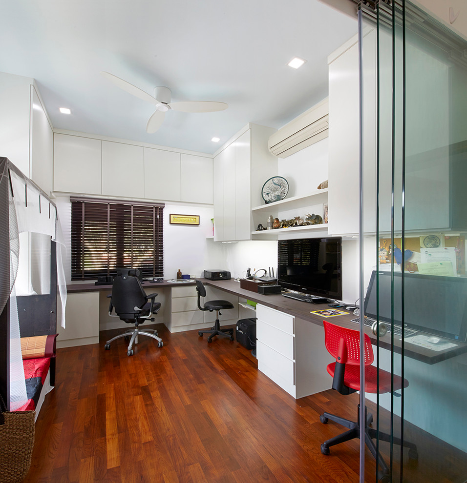 Mid-sized contemporary study room in Singapore with white walls, dark hardwood floors and a built-in desk.