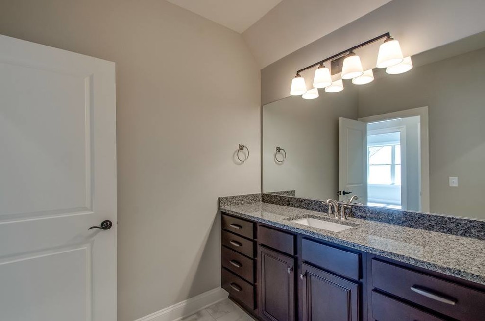 Inspiration for a mid-sized transitional 3/4 gray tile and porcelain tile porcelain tile and gray floor corner shower remodel with recessed-panel cabinets, black cabinets, beige walls, an undermount sink, granite countertops and a hinged shower door