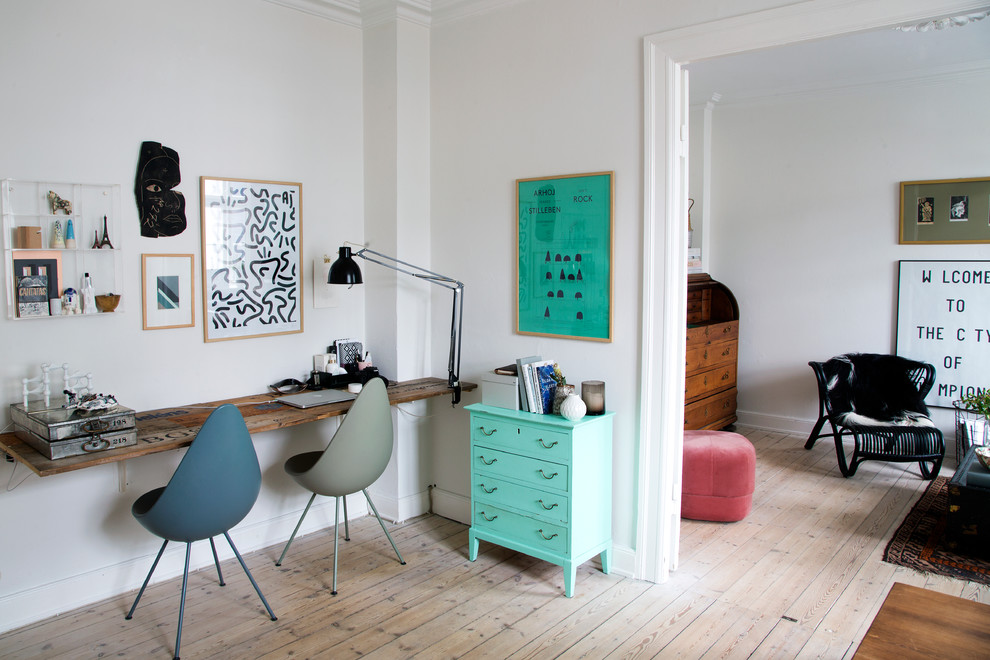 This is an example of a mid-sized scandinavian study room in Copenhagen with white walls, light hardwood floors, a built-in desk and no fireplace.