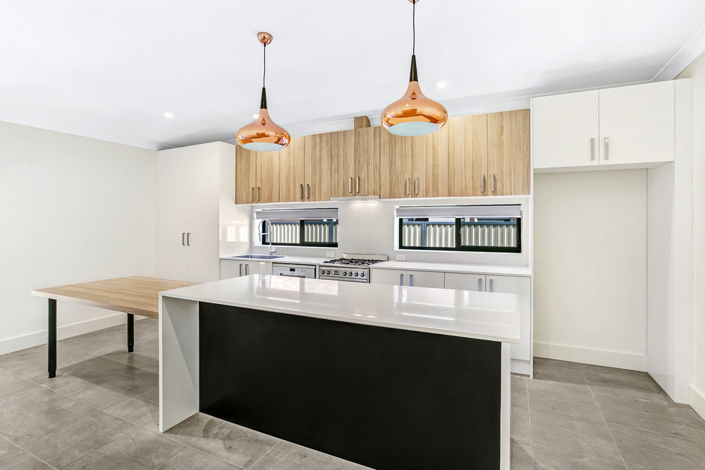Photo of a mid-sized modern single-wall open plan kitchen in Sydney with a drop-in sink, flat-panel cabinets, white cabinets, quartz benchtops, white splashback, stainless steel appliances, porcelain floors, with island, grey floor and white benchtop.