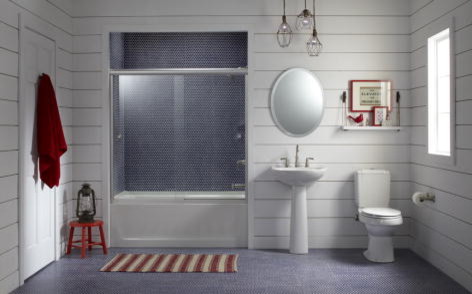 This is an example of a traditional bathroom in Milwaukee with a pedestal sink, an alcove tub, a shower/bathtub combo, a two-piece toilet, blue tile and glass tile.