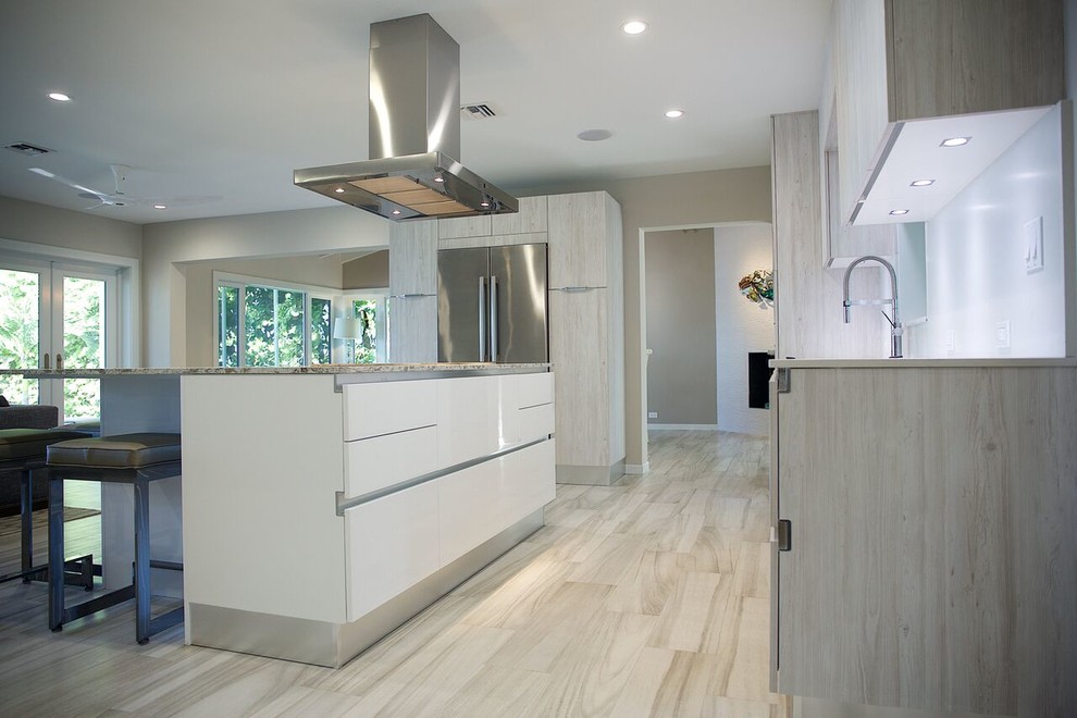 Photo of a mid-sized beach style eat-in kitchen in Miami with a single-bowl sink, flat-panel cabinets, light wood cabinets, quartz benchtops, stainless steel appliances, porcelain floors and with island.